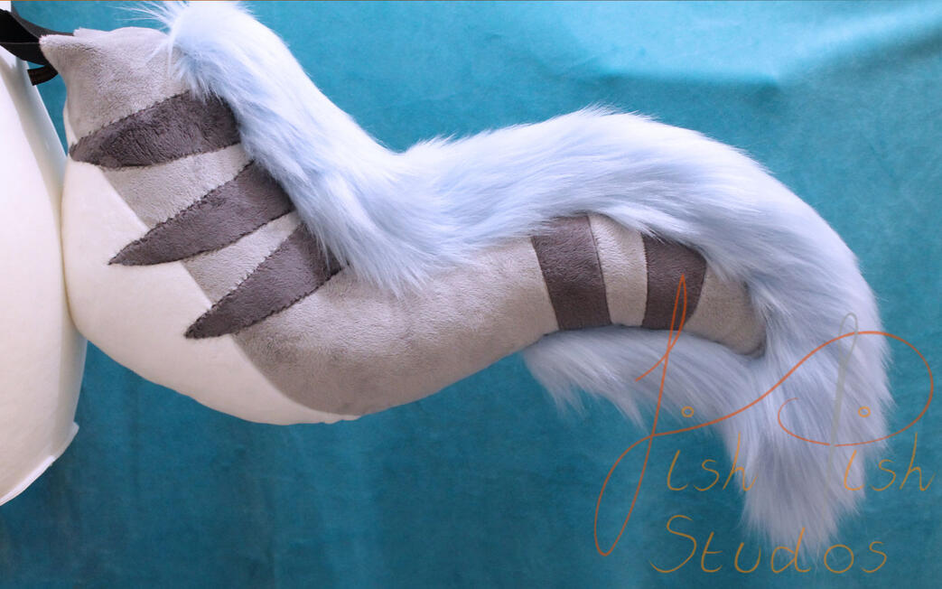 A silvery grey tail with darker grey stripes, a white belly and baby blue faux fur trim. Made from minky and luxury faux fur for fursuits, larp and therian costumes