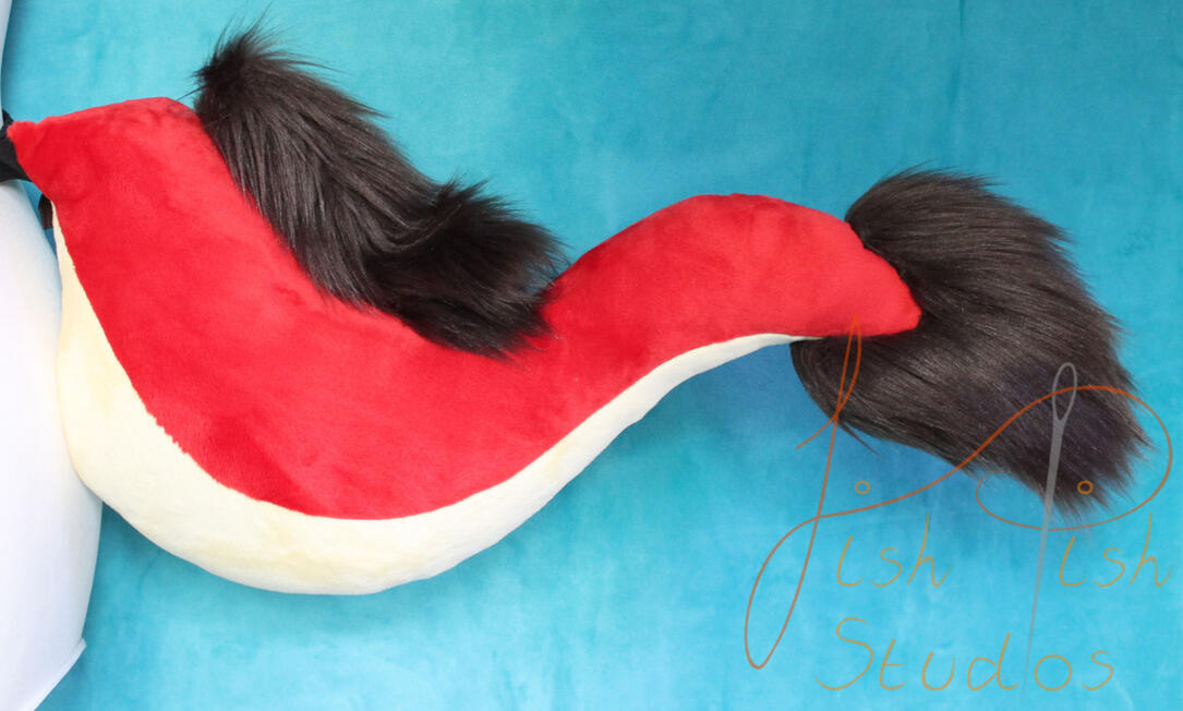 A red dragon tail, with pale yellow belly and brown faux fur accents. Made with minky and luxury faux fur for fursuits, larp and therian costumes