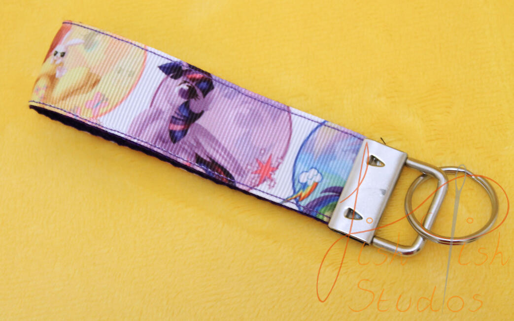 a cute photo showing a my little pony themed keyring made of fabric. It has little artwork of the mane size ponies including twilight sparkle, rarity and rainbowdash. handmade in the UK by fishpish studios